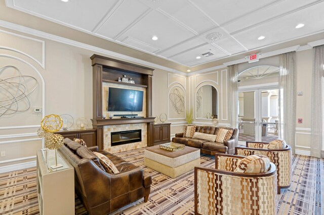 living room with a decorative wall, a glass covered fireplace, coffered ceiling, and ornamental molding