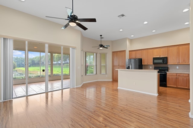 kitchen with decorative backsplash, light countertops, ceiling fan, open floor plan, and black appliances