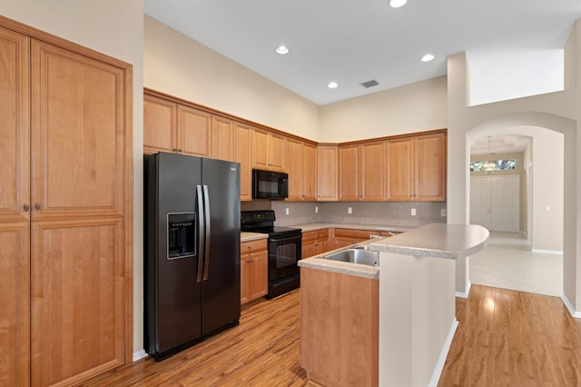 kitchen with visible vents, arched walkways, a sink, black appliances, and backsplash