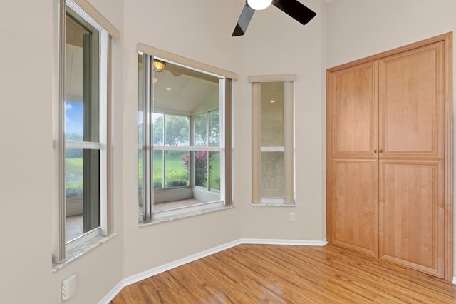 unfurnished bedroom featuring baseboards, ceiling fan, wood finished floors, and a closet