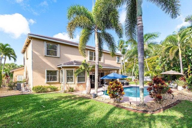 rear view of property featuring cooling unit, a lawn, a patio, an outdoor pool, and stucco siding