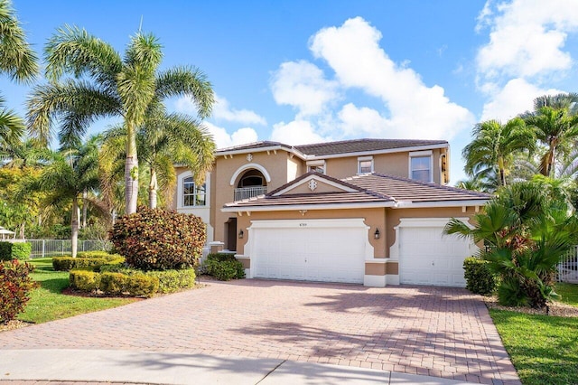 view of front of house featuring a tile roof, decorative driveway, fence, a garage, and stucco siding