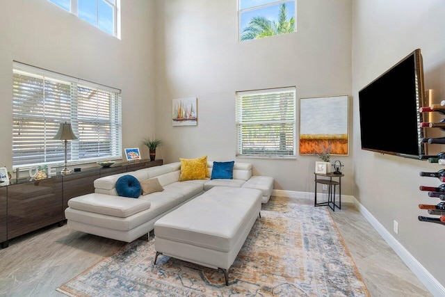 living room featuring a healthy amount of sunlight, baseboards, and a high ceiling