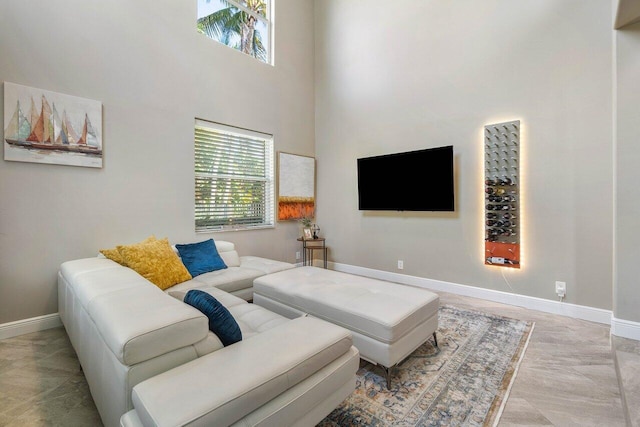 living room with baseboards, a towering ceiling, and plenty of natural light