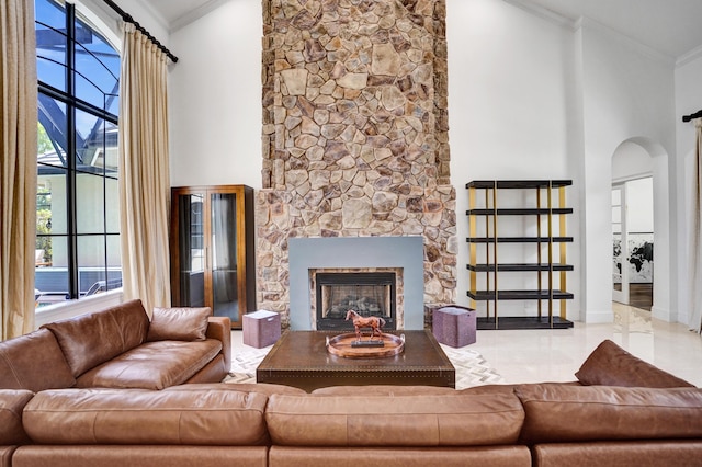 9210 Equus Cir, Boynton Beach, FL 33472 - living room featuring arched walkways, a stone fireplace, a towering ceiling, crown molding, and baseboards