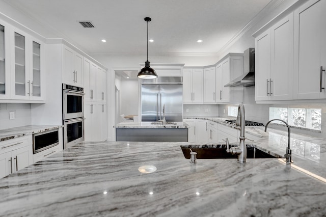 9210 Equus Cir, Boynton Beach, FL 33472 - kitchen featuring built in appliances, wall chimney range hood, tasteful backsplash, glass insert cabinets, and white cabinets