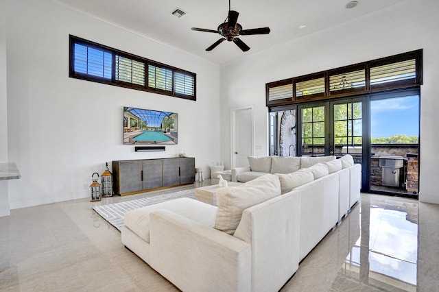 living room featuring a towering ceiling, ceiling fan, crown molding, and baseboards