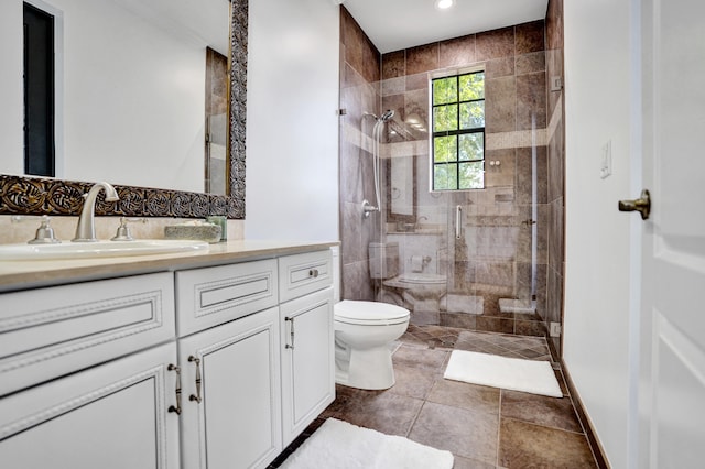 bathroom with toilet, a tile shower, vanity, and recessed lighting