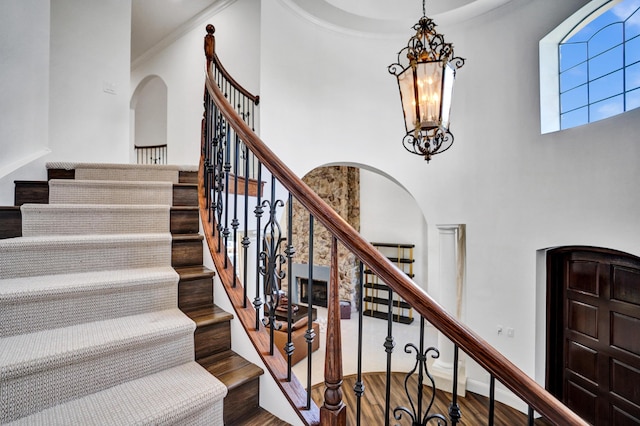 9210 Equus Cir, Boynton Beach, FL 33472 - staircase featuring arched walkways, wood finished floors, a towering ceiling, a chandelier, and ornamental molding