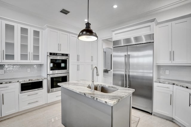 kitchen with built in appliances, a sink, glass insert cabinets, backsplash, and white cabinetry