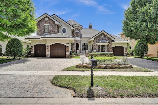 9210 Equus Cir, Boynton Beach, FL 33472 - french country style house with a garage, stone siding, decorative driveway, and stucco siding