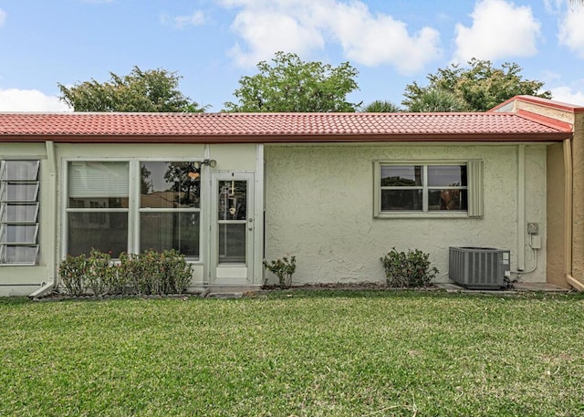104 Lake Helen Dr, West Palm Beach, FL 33411 - back of house with a yard, stucco siding, a tiled roof, and central AC unit