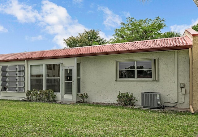 104 Lake Helen Dr, West Palm Beach, FL 33411 - rear view of house with cooling unit, a tiled roof, stucco siding, and a yard