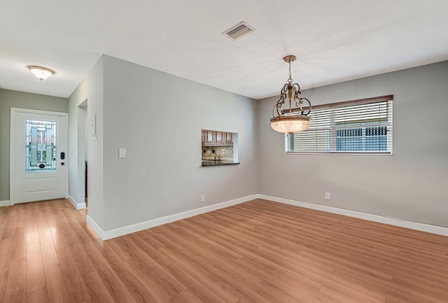104 Lake Helen Dr, West Palm Beach, FL 33411 - unfurnished room with baseboards, light wood finished floors, an inviting chandelier, and visible vents