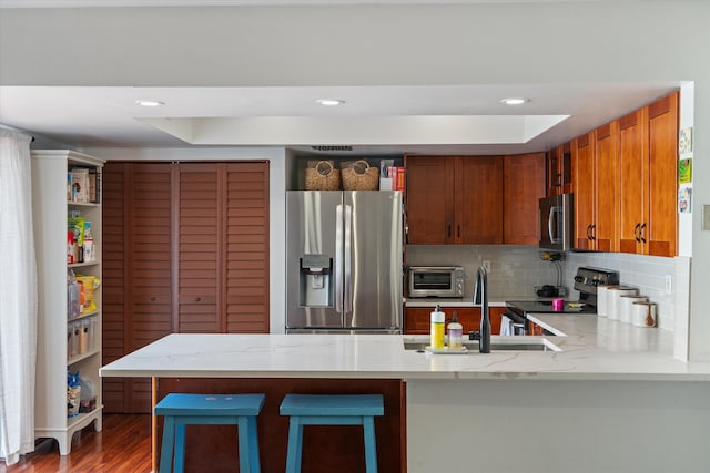 1423 SW 28th Ave, Boynton Beach, FL 33426 - kitchen featuring appliances with stainless steel finishes, a peninsula, light stone counters, decorative backsplash, and a sink