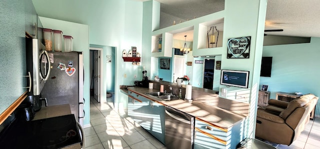kitchen featuring a sink, stainless steel appliances, light tile patterned flooring, a chandelier, and high vaulted ceiling