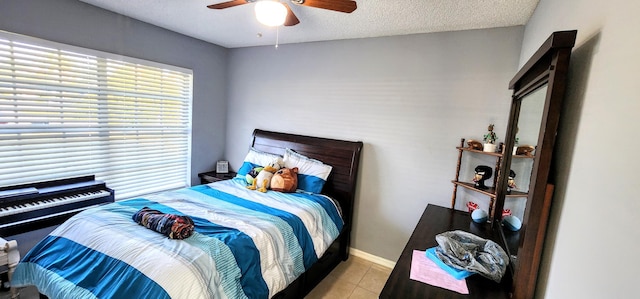 bedroom with light tile patterned floors, a textured ceiling, a ceiling fan, and baseboards