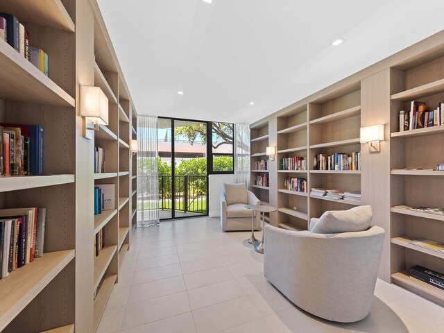 living area featuring light tile patterned floors, built in shelves, and a wall of windows
