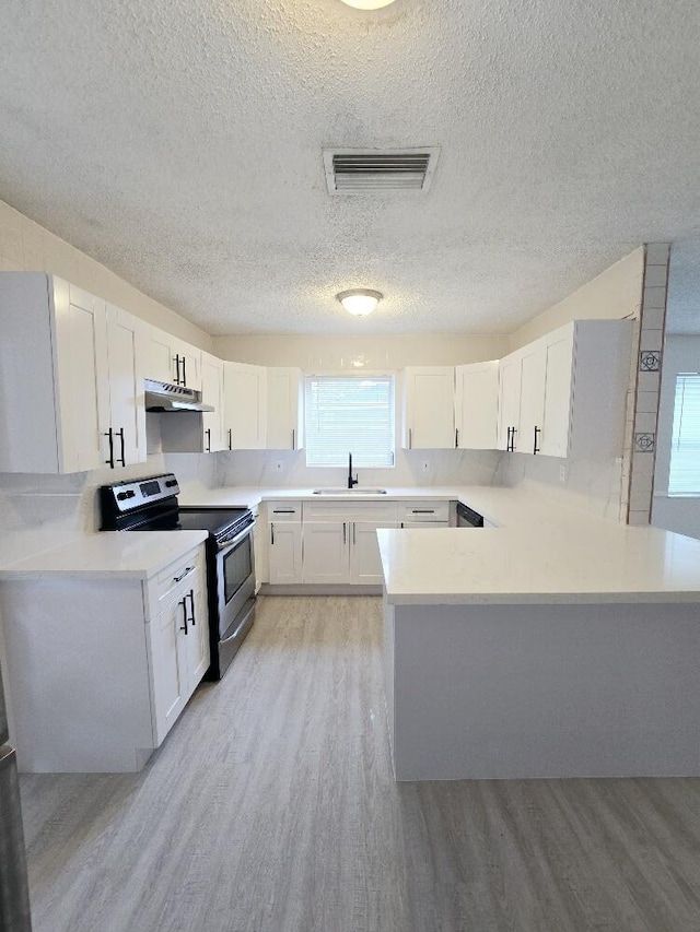 kitchen with stainless steel range with electric stovetop, light wood-style floors, visible vents, and under cabinet range hood