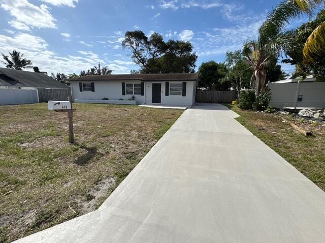 ranch-style home with concrete driveway, a front lawn, and fence