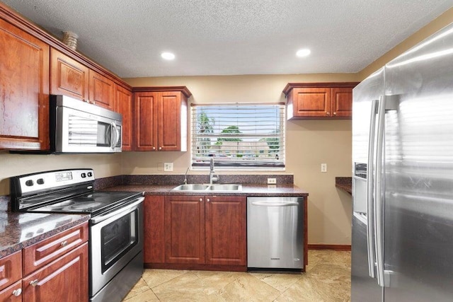 kitchen featuring a textured ceiling, dark countertops, recessed lighting, appliances with stainless steel finishes, and a sink