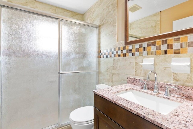 bathroom featuring tile walls, visible vents, a shower stall, toilet, and vanity