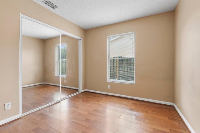 unfurnished bedroom with a closet, baseboards, visible vents, and wood finished floors