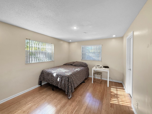 6875 NW 1st Ct, Margate, FL 33063 - bedroom with light wood-style flooring, multiple windows, baseboards, and a textured ceiling