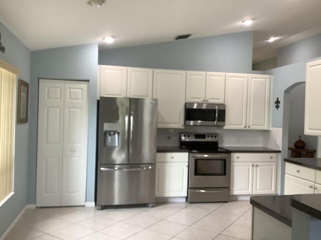 7007 Ashton St, Boynton Beach, FL 33437 - kitchen with dark countertops, lofted ceiling, light tile patterned floors, and appliances with stainless steel finishes