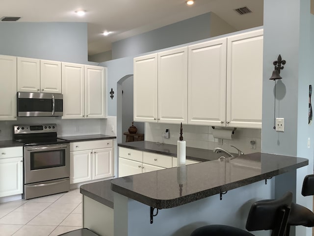 7007 Ashton St, Boynton Beach, FL 33437 - kitchen with visible vents, white cabinets, dark countertops, appliances with stainless steel finishes, and a breakfast bar