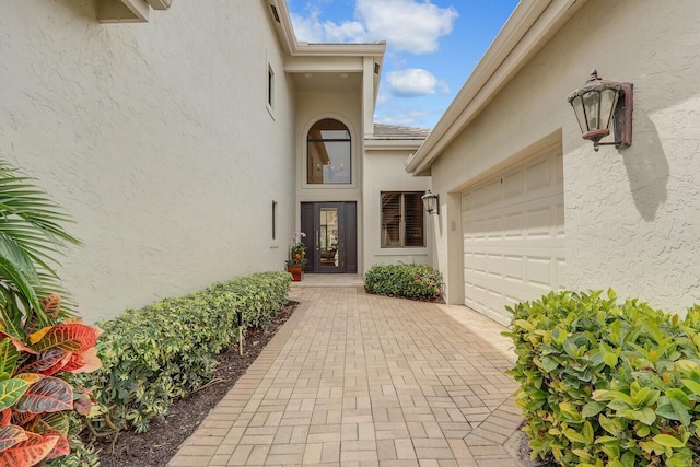 13315 Deauville Dr, Palm Beach Gardens, FL 33410 - doorway to property with stucco siding and a garage