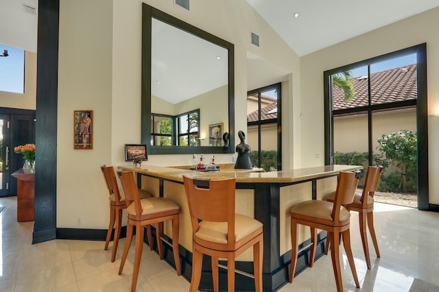 13315 Deauville Dr, Palm Beach Gardens, FL 33410 - bar with light tile patterned floors, indoor wet bar, baseboards, and a wealth of natural light
