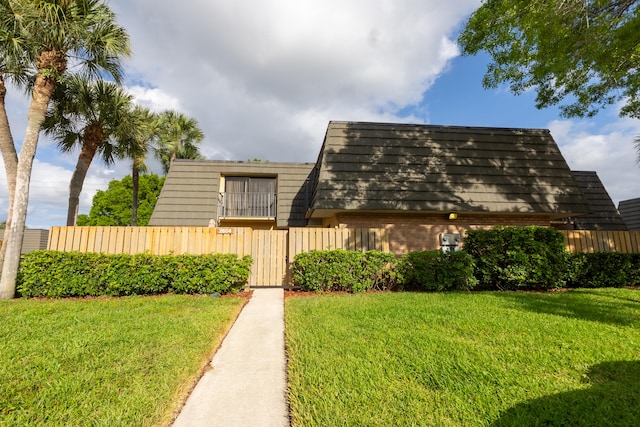 view of front of house with brick siding, fence, and a front lawn
