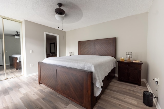 bedroom with ceiling fan, a textured ceiling, baseboards, a closet, and light wood-style flooring
