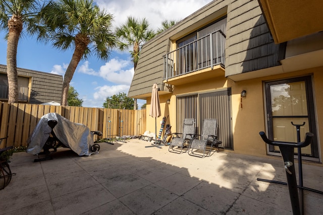 view of patio with fence and a balcony
