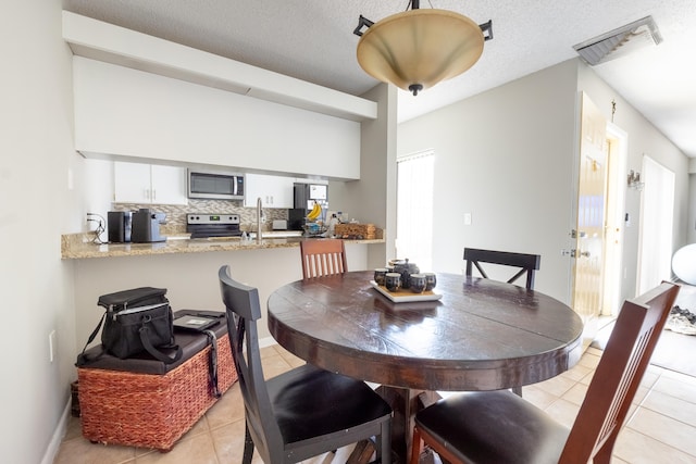 dining space with light tile patterned floors, a textured ceiling, and visible vents