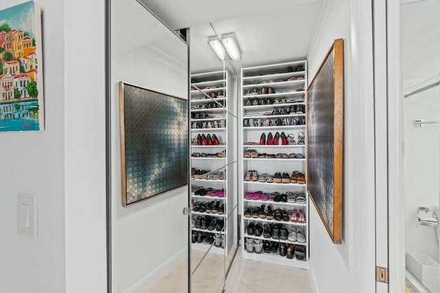 walk in closet featuring marble finish floor