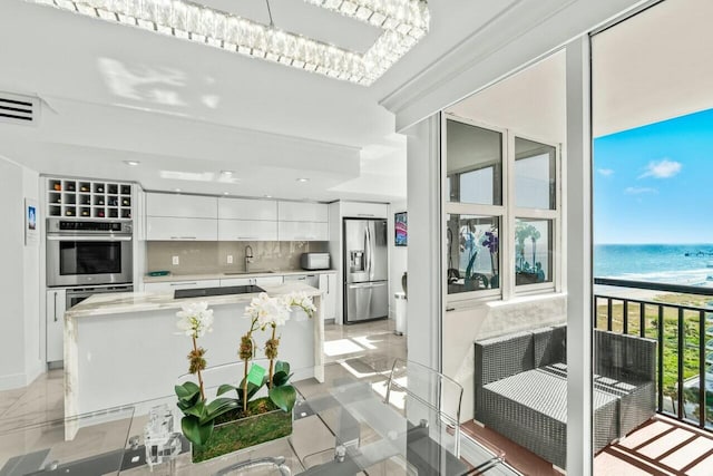 kitchen with a sink, white cabinetry, appliances with stainless steel finishes, modern cabinets, and decorative backsplash