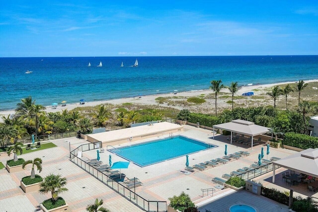 view of pool featuring a water view, fence, a view of the beach, and a gazebo