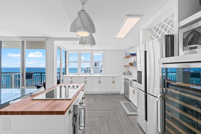 kitchen with white cabinets, wooden counters, appliances with stainless steel finishes, open shelves, and beverage cooler