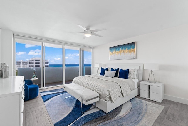 bedroom featuring baseboards, access to exterior, a ceiling fan, and a wall of windows