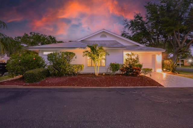 4140 NE Breakwater Dr, Jensen Beach, FL 34957 - view of front of home featuring driveway, an attached garage, a standing seam roof, and metal roof
