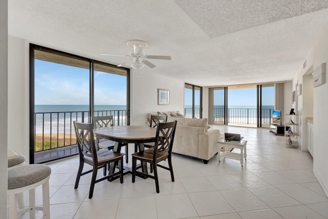 10000 S Ocean Dr S Unit 601, Jensen Beach, FL 34957 - dining space featuring light tile patterned flooring, a water view, a textured ceiling, floor to ceiling windows, and ceiling fan