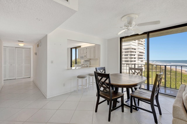 10000 S Ocean Dr S Unit 601, Jensen Beach, FL 34957 - dining room featuring a wall of windows, light tile patterned floors, a view of the beach, baseboards, and ceiling fan