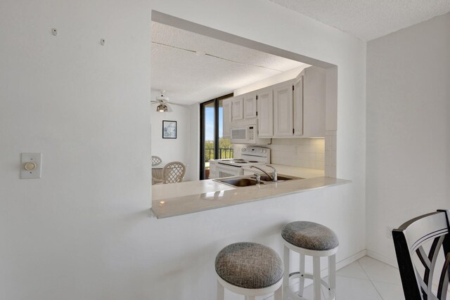 10000 S Ocean Dr S Unit 601, Jensen Beach, FL 34957 - kitchen featuring light countertops, a sink, a textured ceiling, white appliances, and decorative backsplash