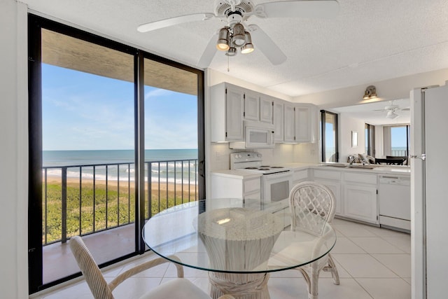 10000 S Ocean Dr S Unit 601, Jensen Beach, FL 34957 - dining room featuring a water view, a textured ceiling, floor to ceiling windows, ceiling fan, and light tile patterned floors
