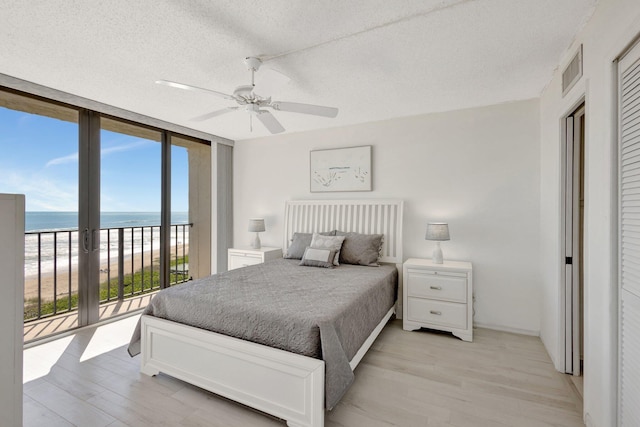 10000 S Ocean Dr S Unit 601, Jensen Beach, FL 34957 - bedroom with a water view, a view of the beach, floor to ceiling windows, access to exterior, and light wood-style flooring