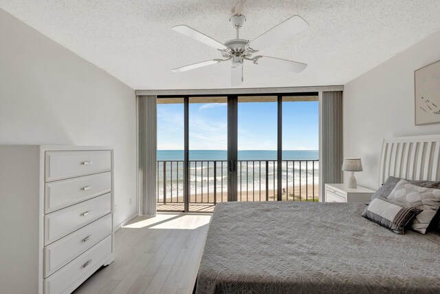 10000 S Ocean Dr S Unit 601, Jensen Beach, FL 34957 - bedroom featuring expansive windows, a water view, a textured ceiling, access to exterior, and wood finished floors