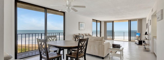 10000 S Ocean Dr S Unit 601, Jensen Beach, FL 34957 - dining space with a water view, a textured ceiling, a ceiling fan, expansive windows, and light tile patterned floors