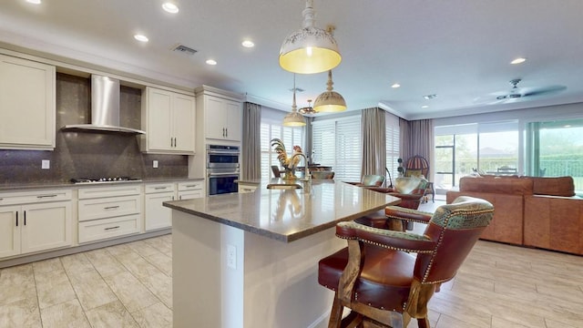 11994 SW Bristol Bay Dr, Port Saint Lucie, FL 34987 - kitchen with gas cooktop, a sink, double oven, open floor plan, and wall chimney range hood